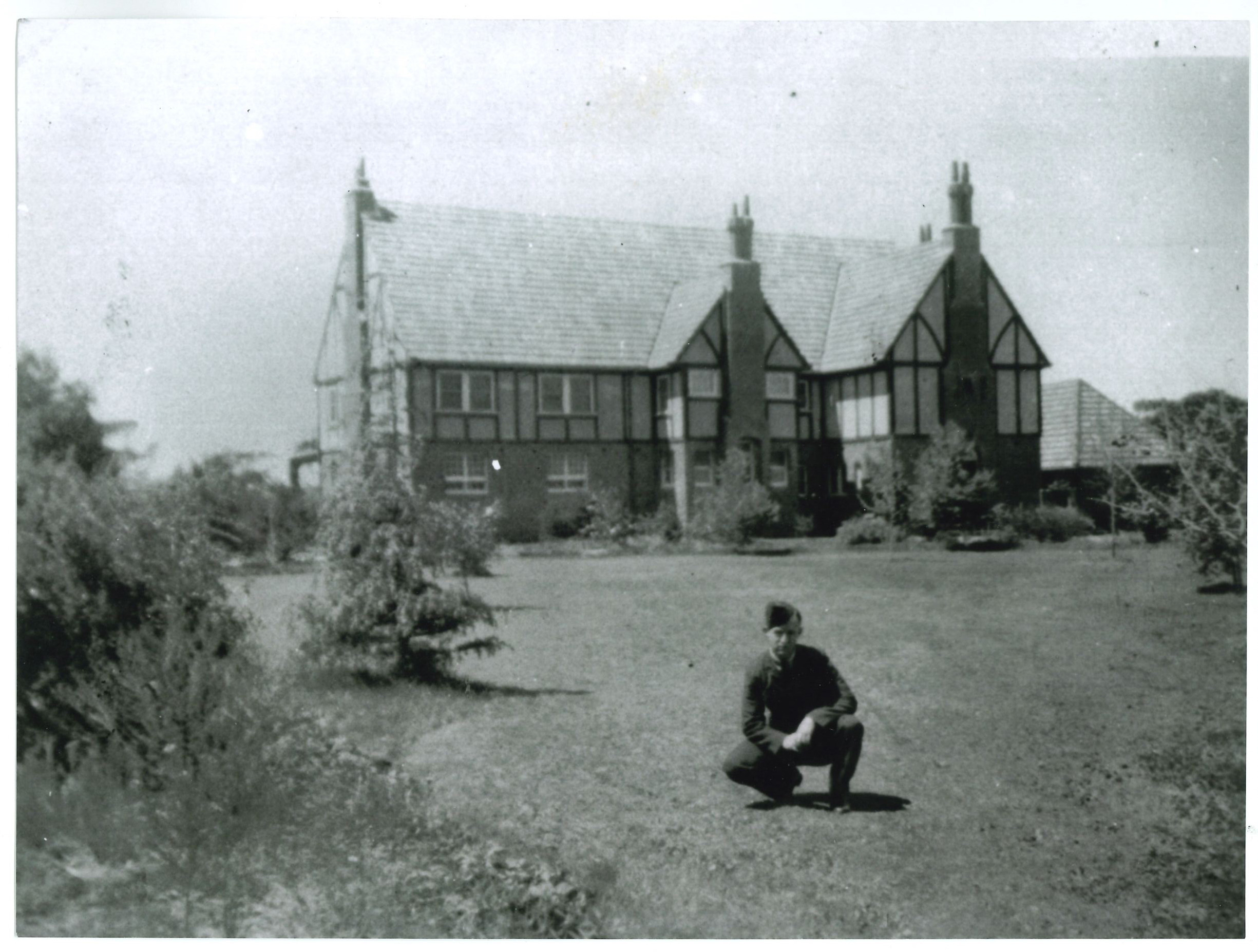A soldier crouches in front of the requisitioned clubhouse during the war years