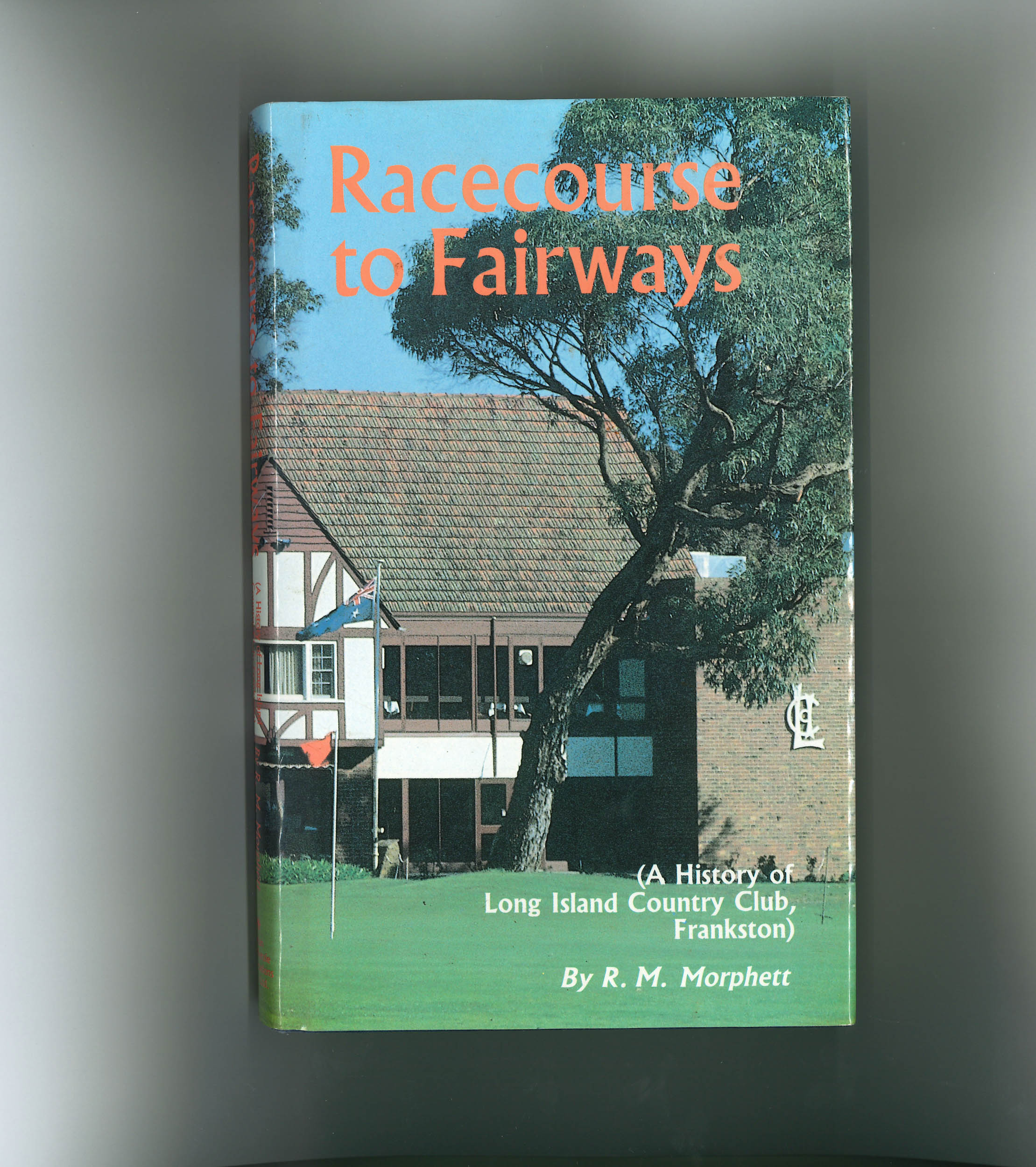 The cover of From Racecourse to Fairways by R.M. Morphett, showing the original clubhouse on a sunny day
